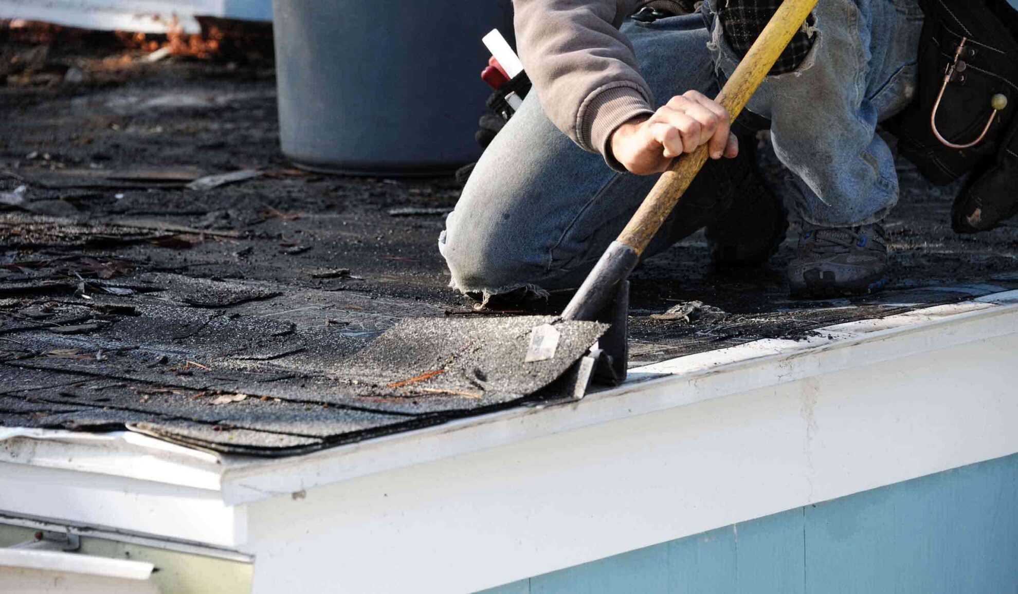 contractor close up with shovel removing damaged asphalt shingles at roof chatsworth ga